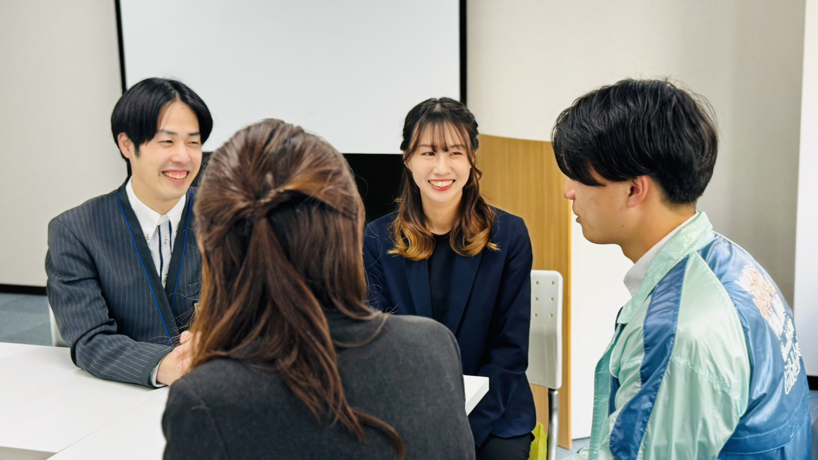 明るい研修ルームで、リラックスして相談や会話を楽しむ女性スタッフたちの様子。