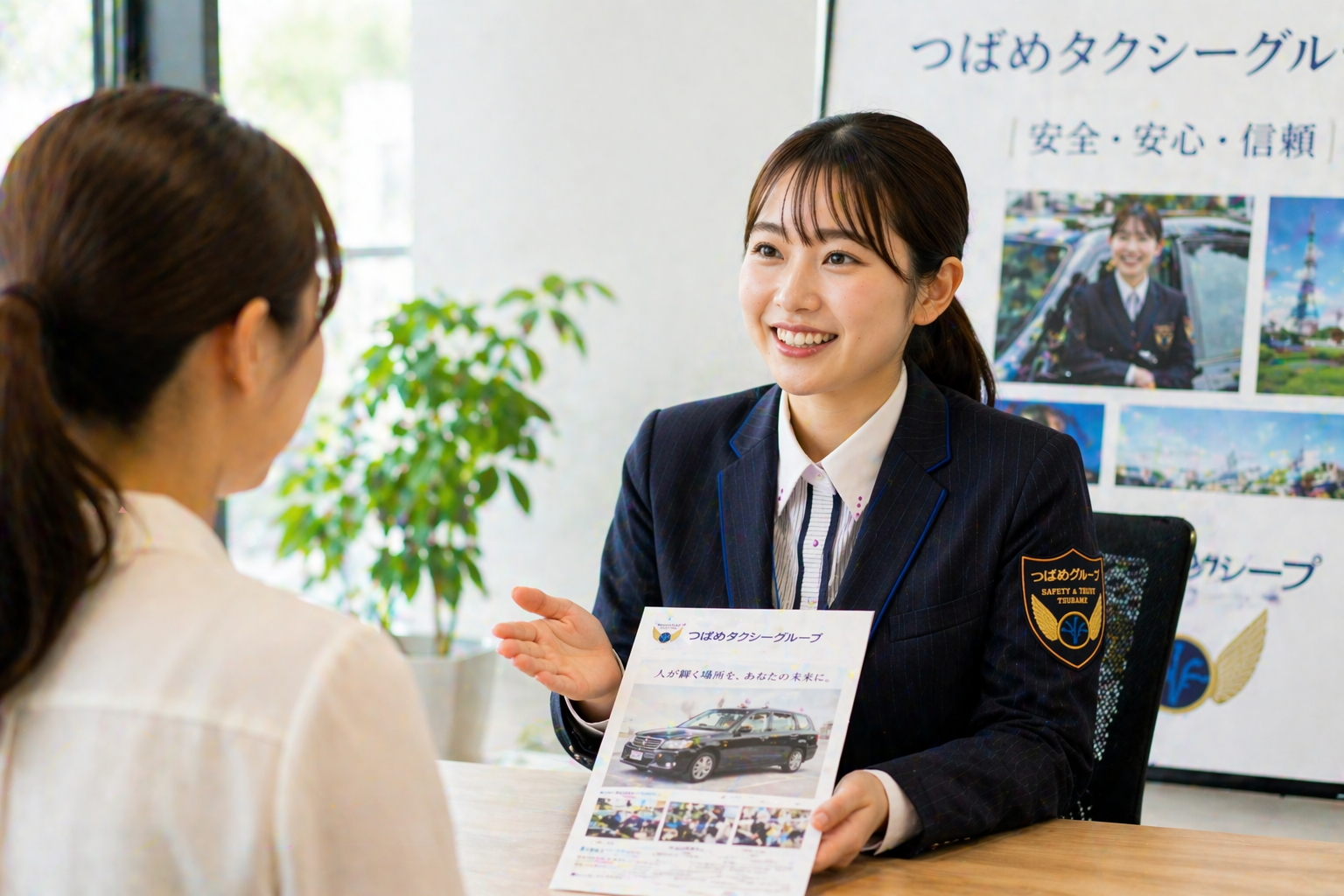つばめタクシーグループの制服を着た女性スタッフが応募希望者と向かい合って笑顔で案内し、安心して転職相談できる職場環境を表現した画像