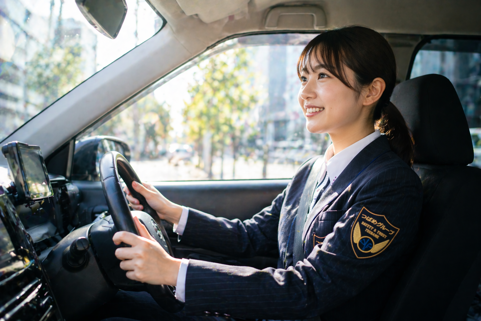 つばめタクシーグループの制服を着た女性ドライバーが車内で笑顔で運転し、未経験から安心して働ける研修とサポート体制を表現した画像